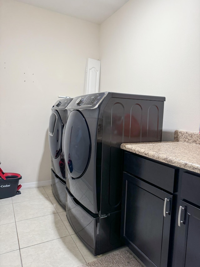 washroom featuring washing machine and dryer, cabinets, and light tile patterned flooring