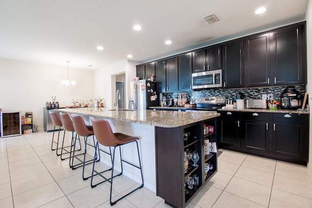 kitchen featuring a kitchen island with sink, decorative light fixtures, and stainless steel appliances