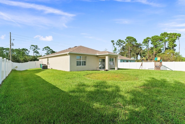 back of house featuring a playground, a lawn, and central air condition unit