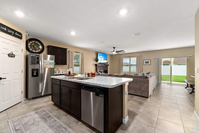 kitchen featuring dark brown cabinets, stainless steel appliances, ceiling fan, sink, and a center island with sink