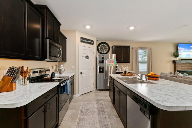 kitchen with light tile patterned floors, sink, appliances with stainless steel finishes, and an island with sink