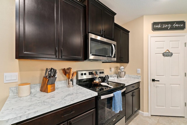 kitchen featuring dark brown cabinets, light tile patterned floors, and stainless steel appliances