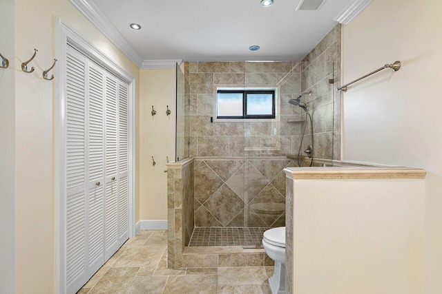 bathroom featuring ornamental molding, toilet, and tiled shower