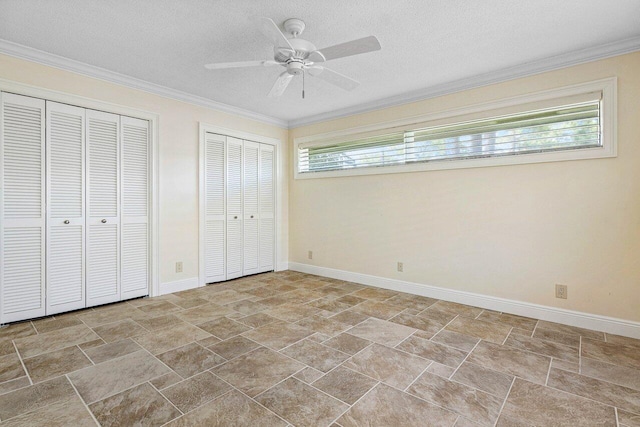 unfurnished bedroom with ceiling fan, multiple closets, a textured ceiling, and crown molding