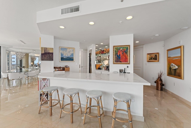 kitchen featuring light stone countertops, kitchen peninsula, a breakfast bar area, and light tile patterned flooring