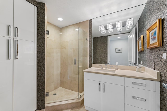 bathroom with a shower with door, tile walls, and vanity