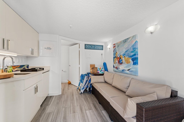 living room with sink, a textured ceiling, and light hardwood / wood-style flooring