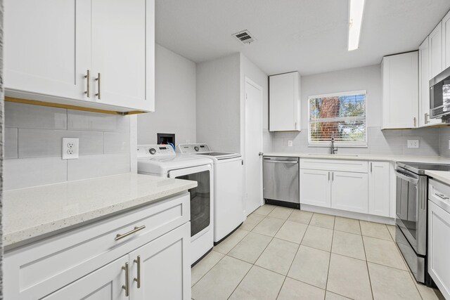 kitchen featuring appliances with stainless steel finishes, white cabinetry, independent washer and dryer, and sink