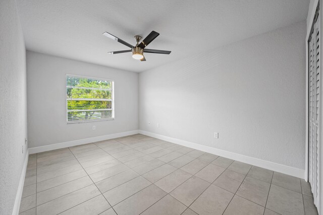 tiled empty room with a textured ceiling and ceiling fan