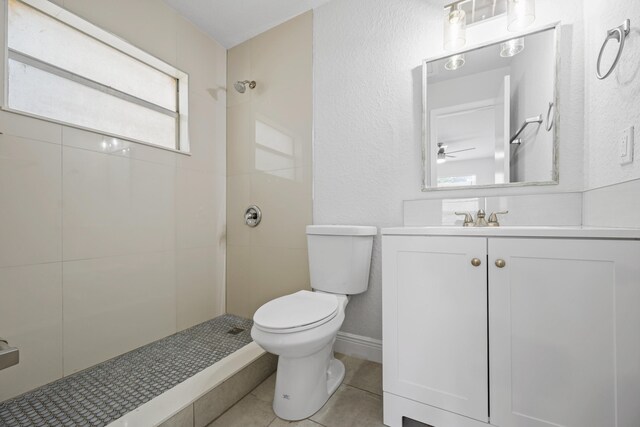 bathroom with vanity, tiled shower, toilet, tile patterned floors, and ceiling fan