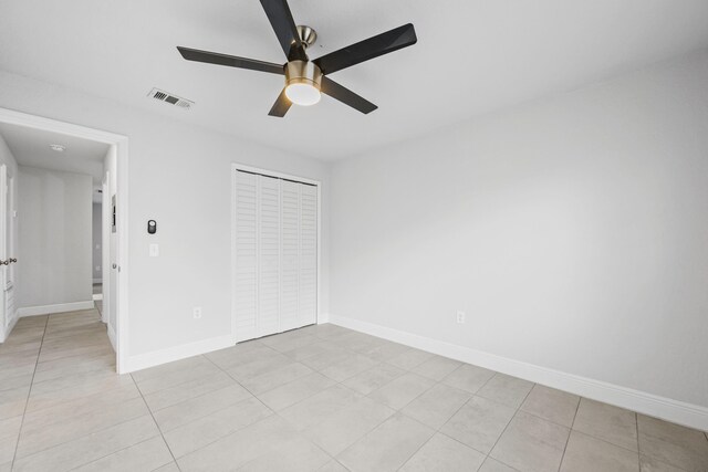 unfurnished bedroom with light tile patterned flooring, ceiling fan, and a closet