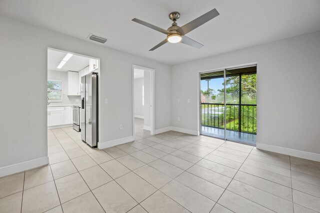 tiled empty room with a healthy amount of sunlight and ceiling fan