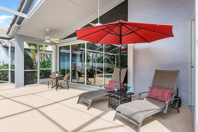 view of patio featuring ceiling fan and glass enclosure