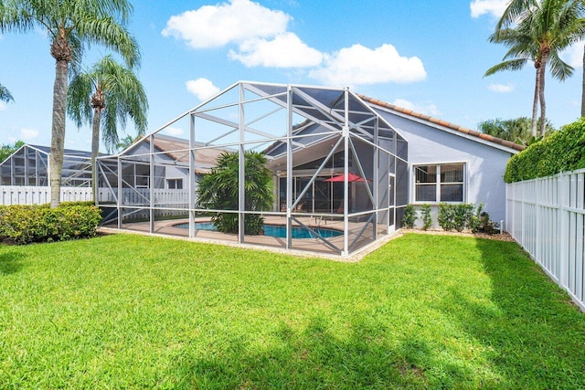 rear view of property with a lawn and glass enclosure