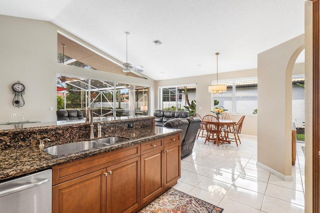 kitchen with dark stone countertops, lofted ceiling, ceiling fan, and stainless steel dishwasher