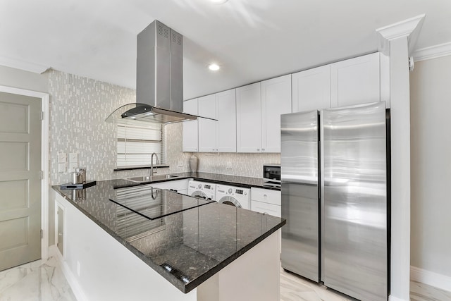 kitchen with black appliances, sink, wall chimney exhaust hood, washer / dryer, and white cabinetry