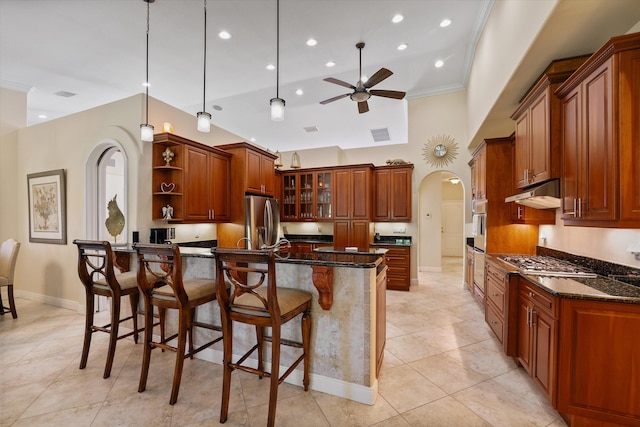 kitchen featuring dark stone counters, pendant lighting, a kitchen bar, appliances with stainless steel finishes, and ceiling fan