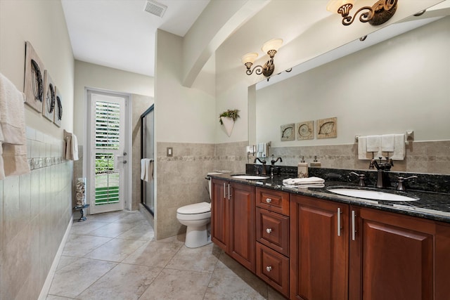 bathroom with tile walls, a shower with door, vanity, and toilet