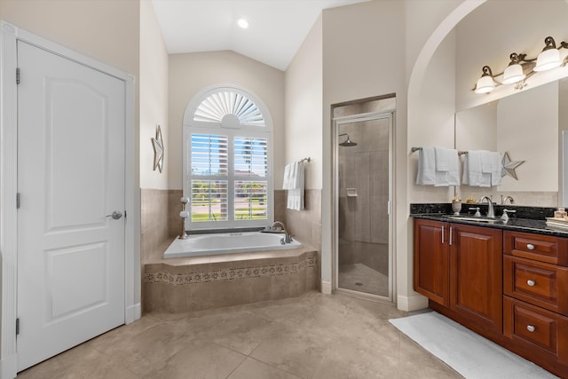 bathroom with shower with separate bathtub, vanity, vaulted ceiling, and tile patterned floors