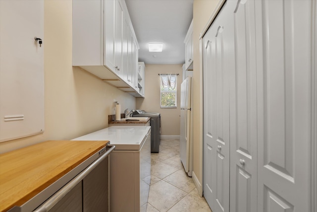 laundry room with cabinets, light tile patterned floors, and washing machine and clothes dryer