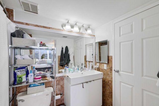 bathroom featuring tile walls, vanity, and toilet