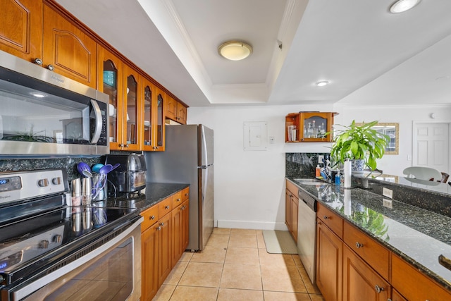 kitchen featuring light tile patterned flooring, ornamental molding, tasteful backsplash, appliances with stainless steel finishes, and dark stone counters