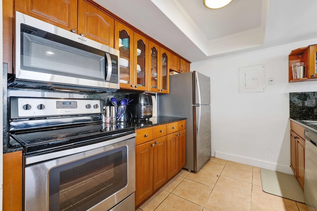 kitchen featuring light tile patterned flooring, tasteful backsplash, a raised ceiling, stainless steel appliances, and ornamental molding