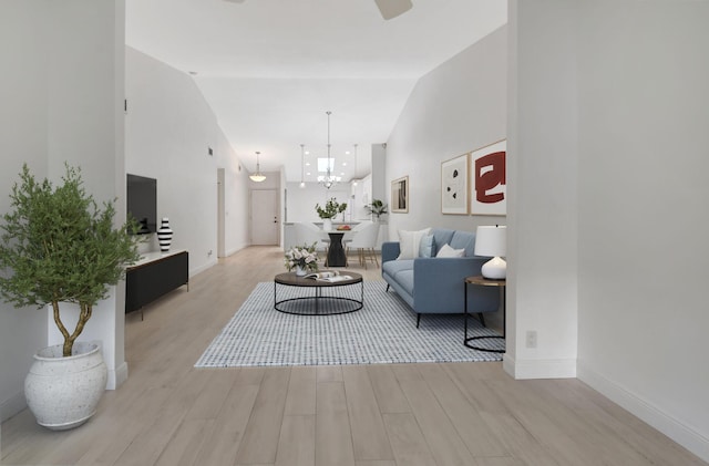 living room featuring a chandelier, lofted ceiling, and light hardwood / wood-style flooring