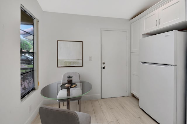 kitchen with white fridge, white cabinetry, and light hardwood / wood-style flooring