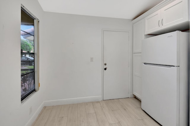 kitchen with white cabinetry, light wood-type flooring, and white refrigerator