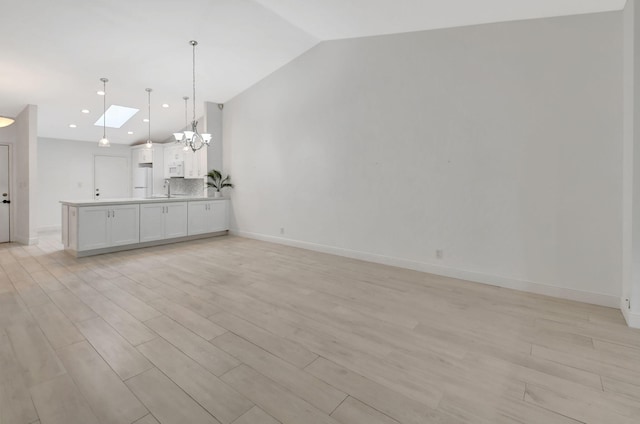 unfurnished living room with light hardwood / wood-style floors, an inviting chandelier, and lofted ceiling with skylight