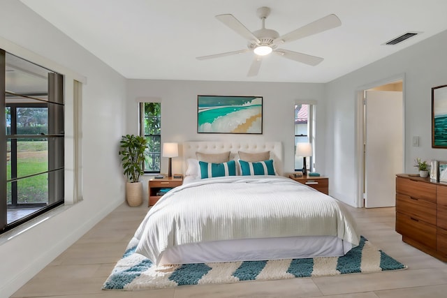 bedroom featuring ceiling fan, light hardwood / wood-style flooring, and multiple windows