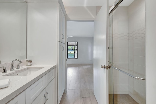 bathroom featuring vanity, wood-type flooring, and a shower with door