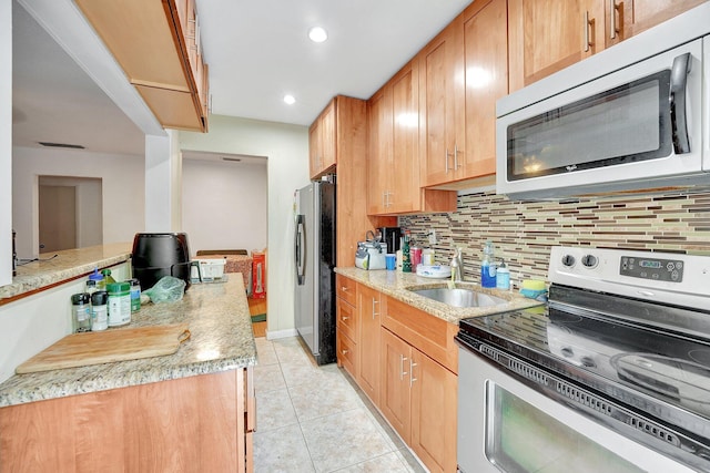 kitchen with sink, light stone countertops, light tile patterned floors, tasteful backsplash, and stainless steel appliances