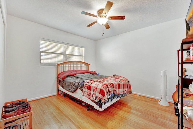 bedroom with a textured ceiling, hardwood / wood-style flooring, and ceiling fan