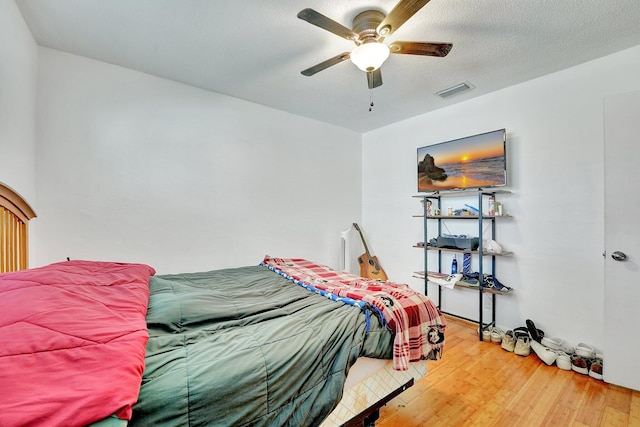 bedroom featuring ceiling fan, hardwood / wood-style floors, and a textured ceiling