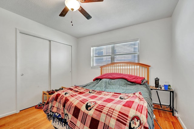 bedroom featuring hardwood / wood-style floors, a textured ceiling, a closet, and ceiling fan