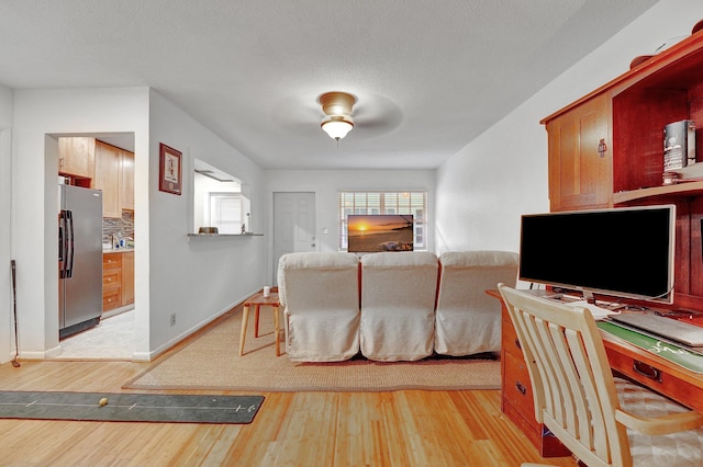 bedroom featuring stainless steel refrigerator, ceiling fan, a textured ceiling, and light wood-type flooring