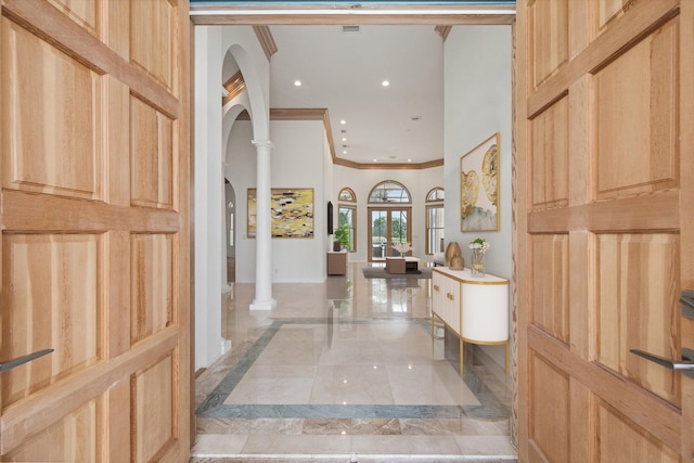 foyer entrance with decorative columns, french doors, and ornamental molding