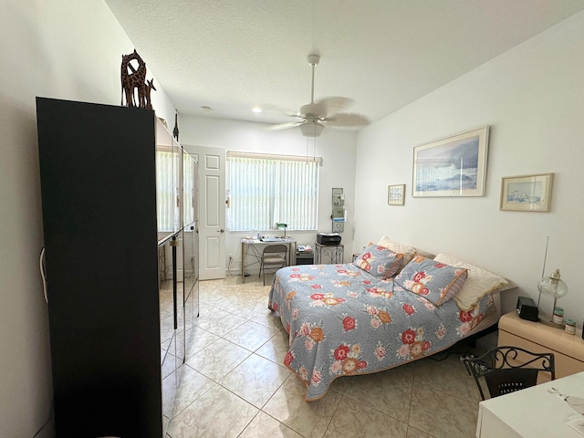 bedroom with ceiling fan, light tile patterned floors, and a textured ceiling