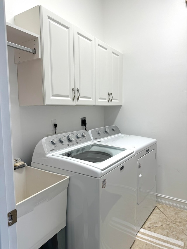 laundry room with light tile patterned floors, cabinets, washing machine and dryer, and sink