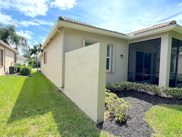 view of home's exterior with a lawn and central AC