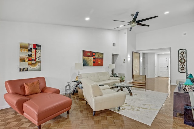 living room with ceiling fan, a towering ceiling, and light parquet floors