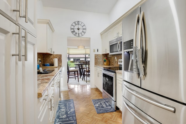 kitchen featuring light stone countertops, tasteful backsplash, stainless steel appliances, light parquet floors, and white cabinetry