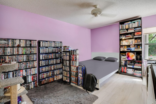 bedroom with ceiling fan, a textured ceiling, and light wood-type flooring