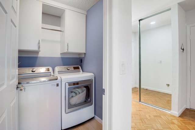 laundry area featuring cabinets, a textured ceiling, light parquet floors, and washer and clothes dryer