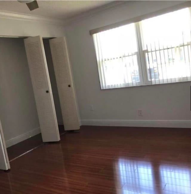 unfurnished bedroom with dark wood-type flooring and ornamental molding