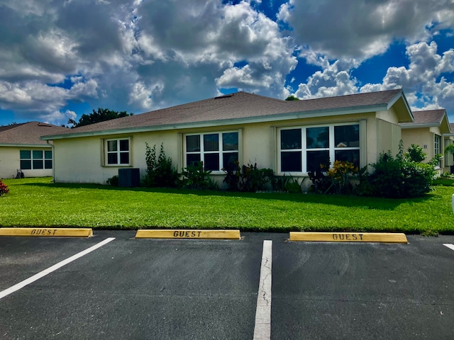 ranch-style house with central air condition unit and a front yard