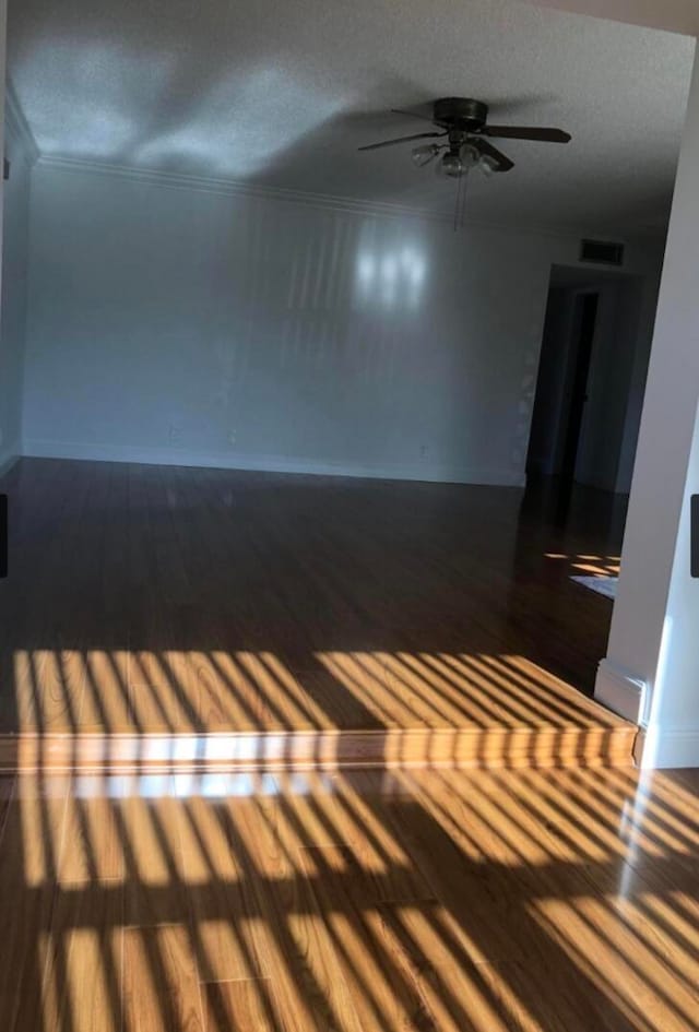 empty room featuring ornamental molding, a textured ceiling, ceiling fan, and dark hardwood / wood-style floors