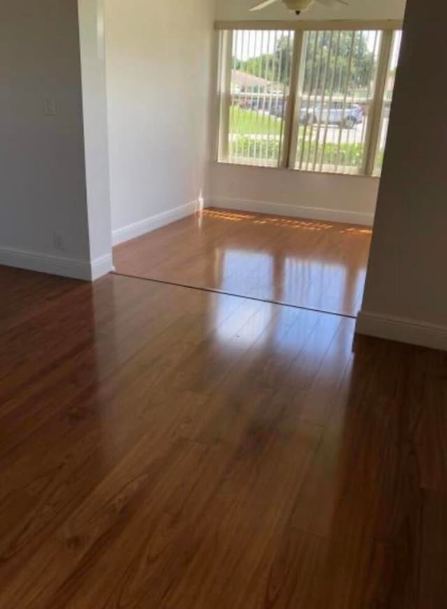 unfurnished room featuring dark wood-type flooring and ceiling fan